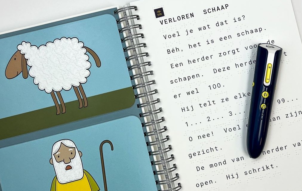 Afbeelding van 2 pagina's van de Peuterbijbel met aan de linkerkant een voelbare afbeelding van een schaap en herder en aan de rechterkant het verhaal over het Verloren Schaap in grootletter en braille, en op het boek liggend de leespen SAM.