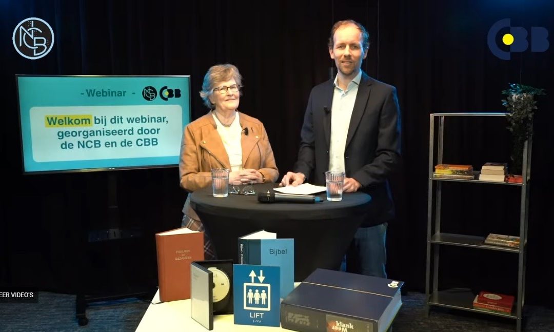 Links op de afbeelding is een tv-scherm te zien, met daarop tekst. Rechts daarvan staan twee personen aan een statafel. Voor hen staat lectuur in diverse leesvormen. Rechts in beeld staat een kast met een paar voorwerpen erin.